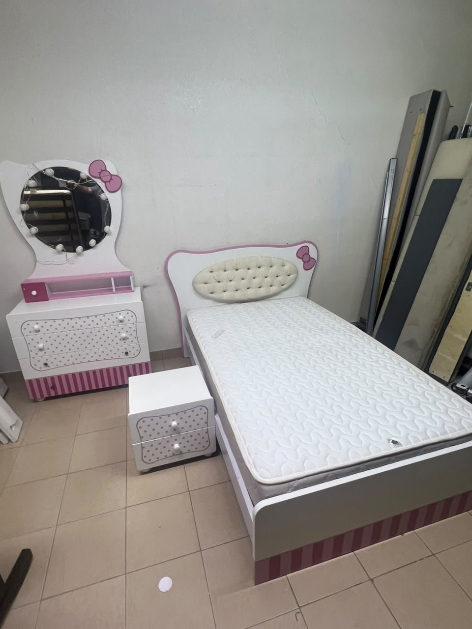 A girls' bedroom featuring a white and pink color scheme, including a bed with bedding, a storage table with an illuminated mirror, and a bedside table. - Image 6