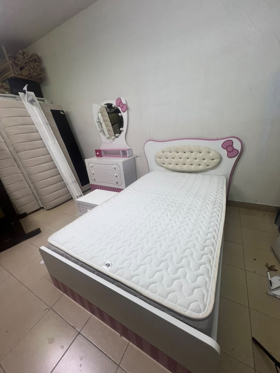 A girls' bedroom featuring a white and pink color scheme, including a bed with bedding, a storage table with an illuminated mirror, and a bedside table. - Image 7