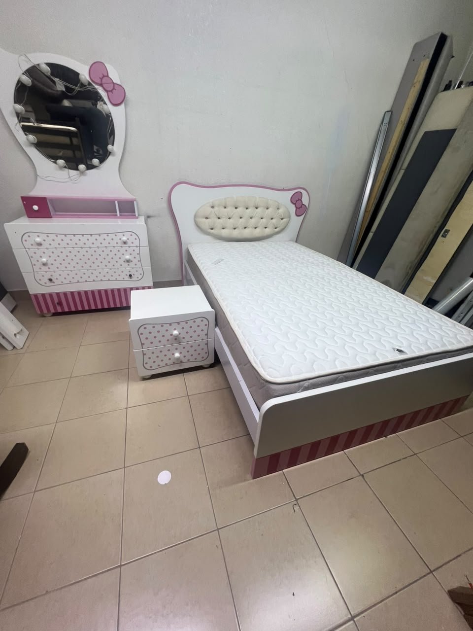 A girls' bedroom featuring a white and pink color scheme, including a bed with bedding, a storage table with an illuminated mirror, and a bedside table. - Image 9