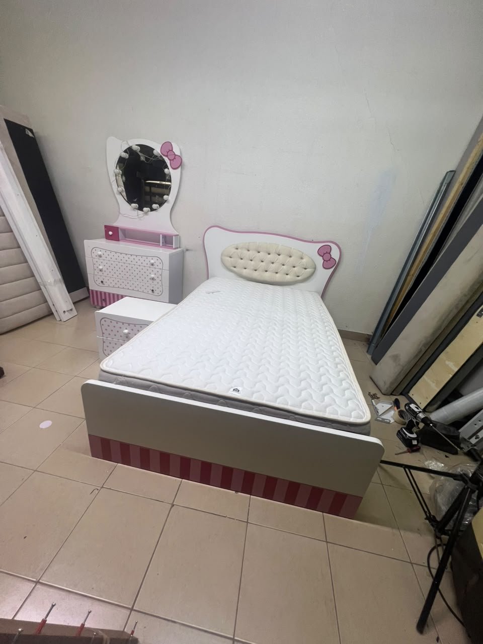 A girls' bedroom featuring a white and pink color scheme, including a bed with bedding, a storage table with an illuminated mirror, and a bedside table. - Image 10