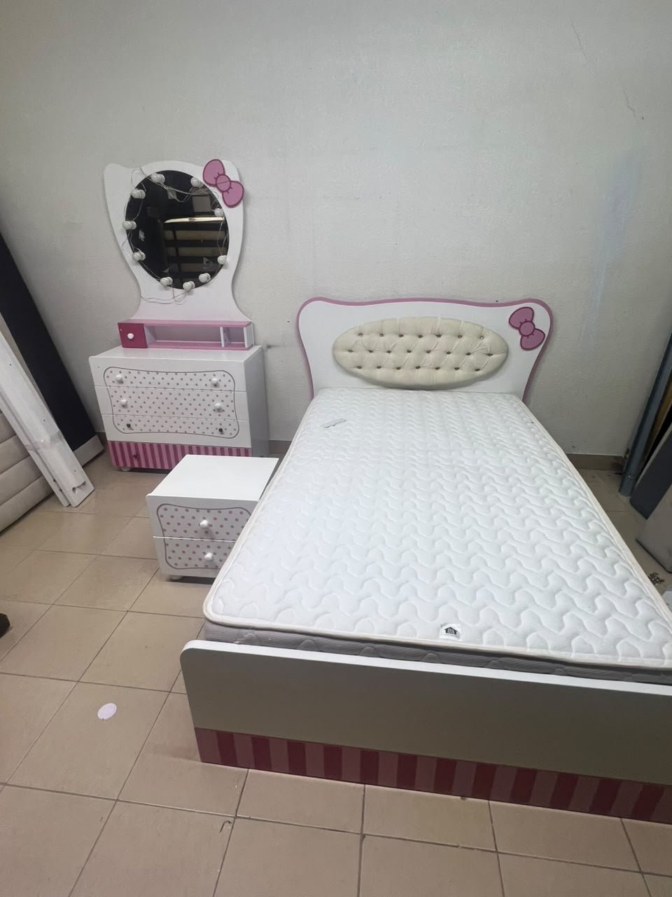 A girls' bedroom featuring a white and pink color scheme, including a bed with bedding, a storage table with an illuminated mirror, and a bedside table. - Image 11