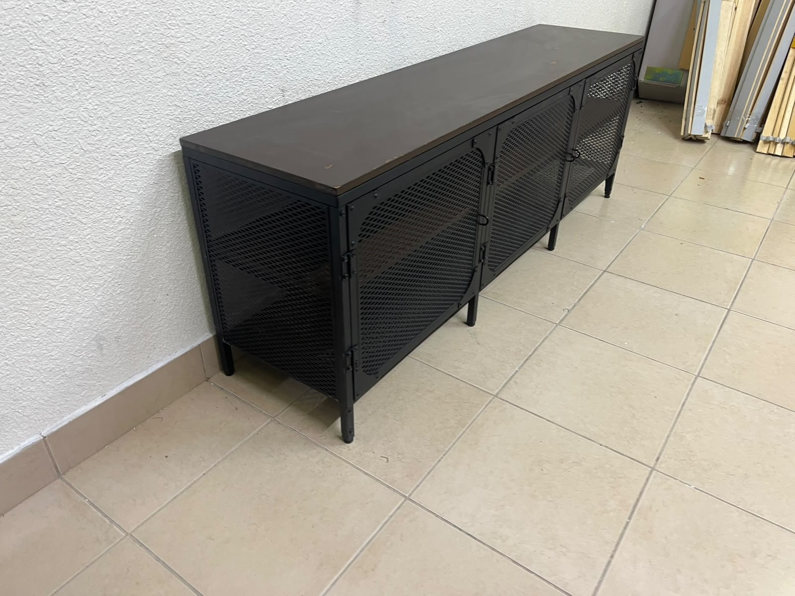 The FJÄLLBO TV unit from IKEA, featuring an industrial design with a solid wood top and black metal mesh doors.