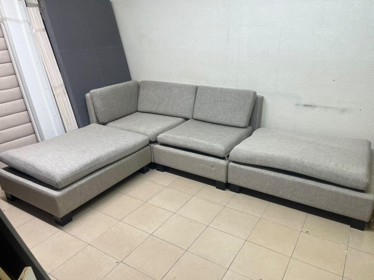 This appears to be a light gray fabric modular sofa, featuring matching ottomans and low, dark block-style legs. - Image 2