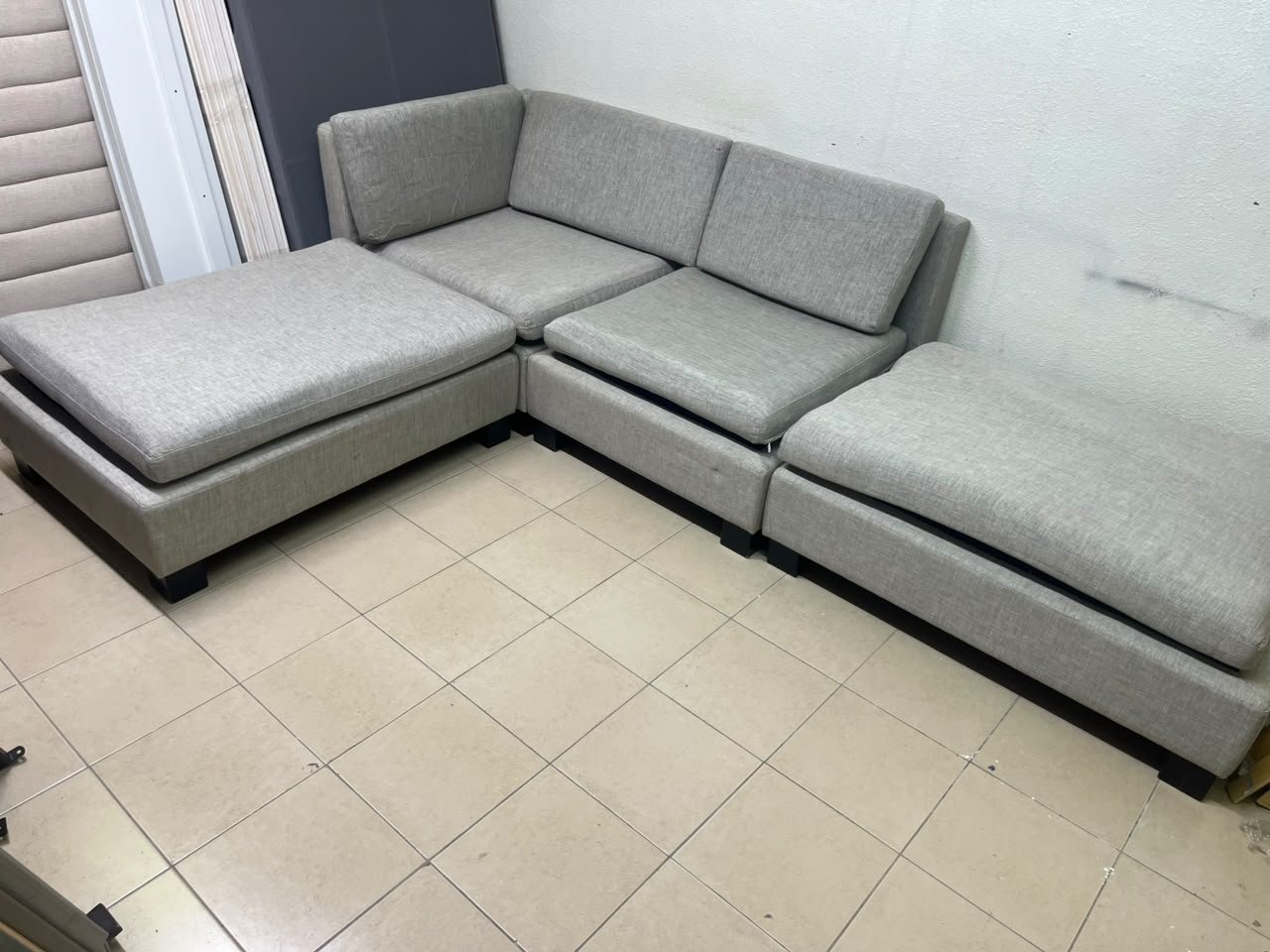 This appears to be a light gray fabric modular sofa, featuring matching ottomans and low, dark block-style legs. - Image 3