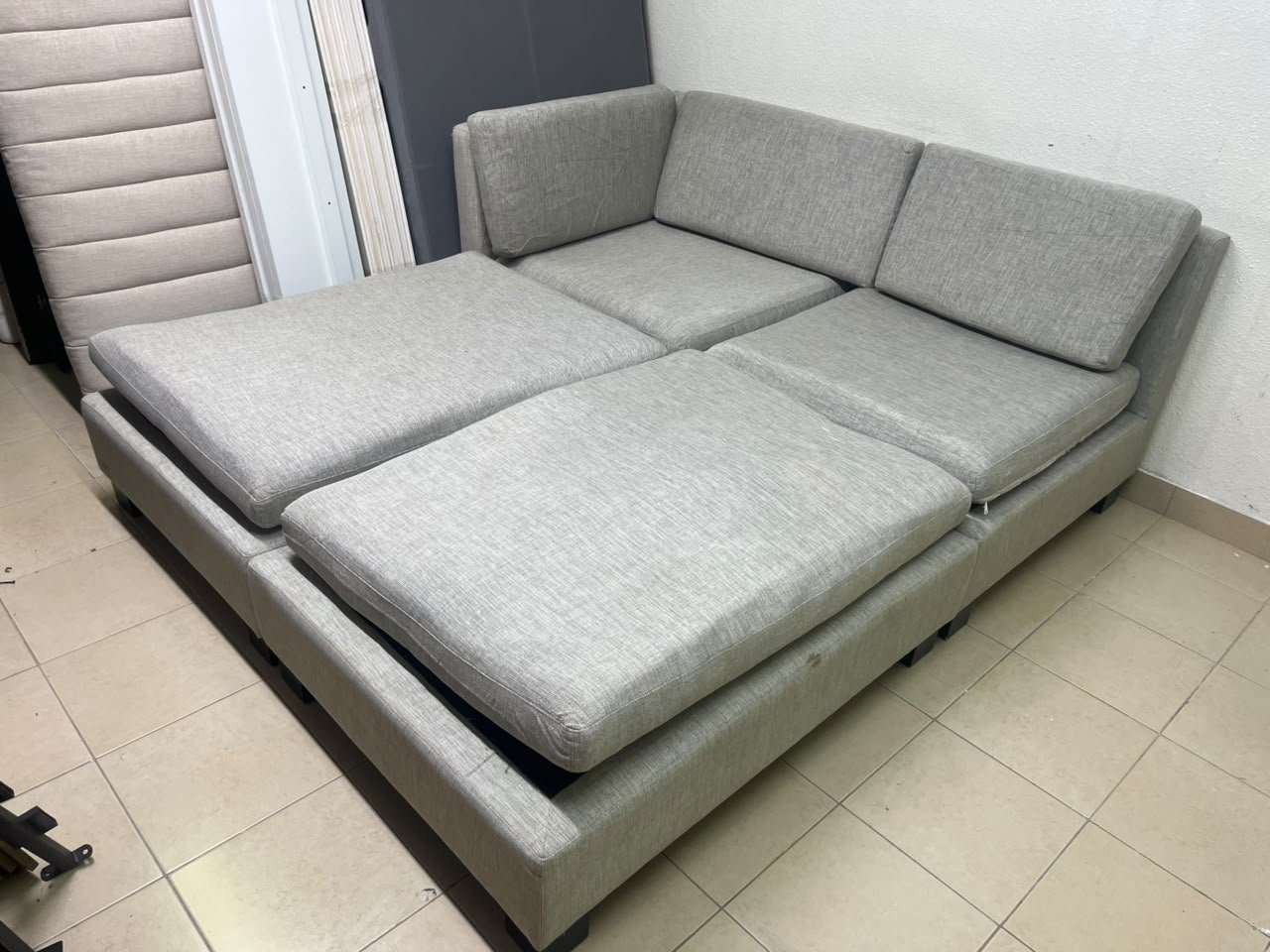 This appears to be a light gray fabric modular sofa, featuring matching ottomans and low, dark block-style legs. - Image 4