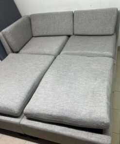 This appears to be a light gray fabric modular sofa, featuring matching ottomans and low, dark block-style legs.