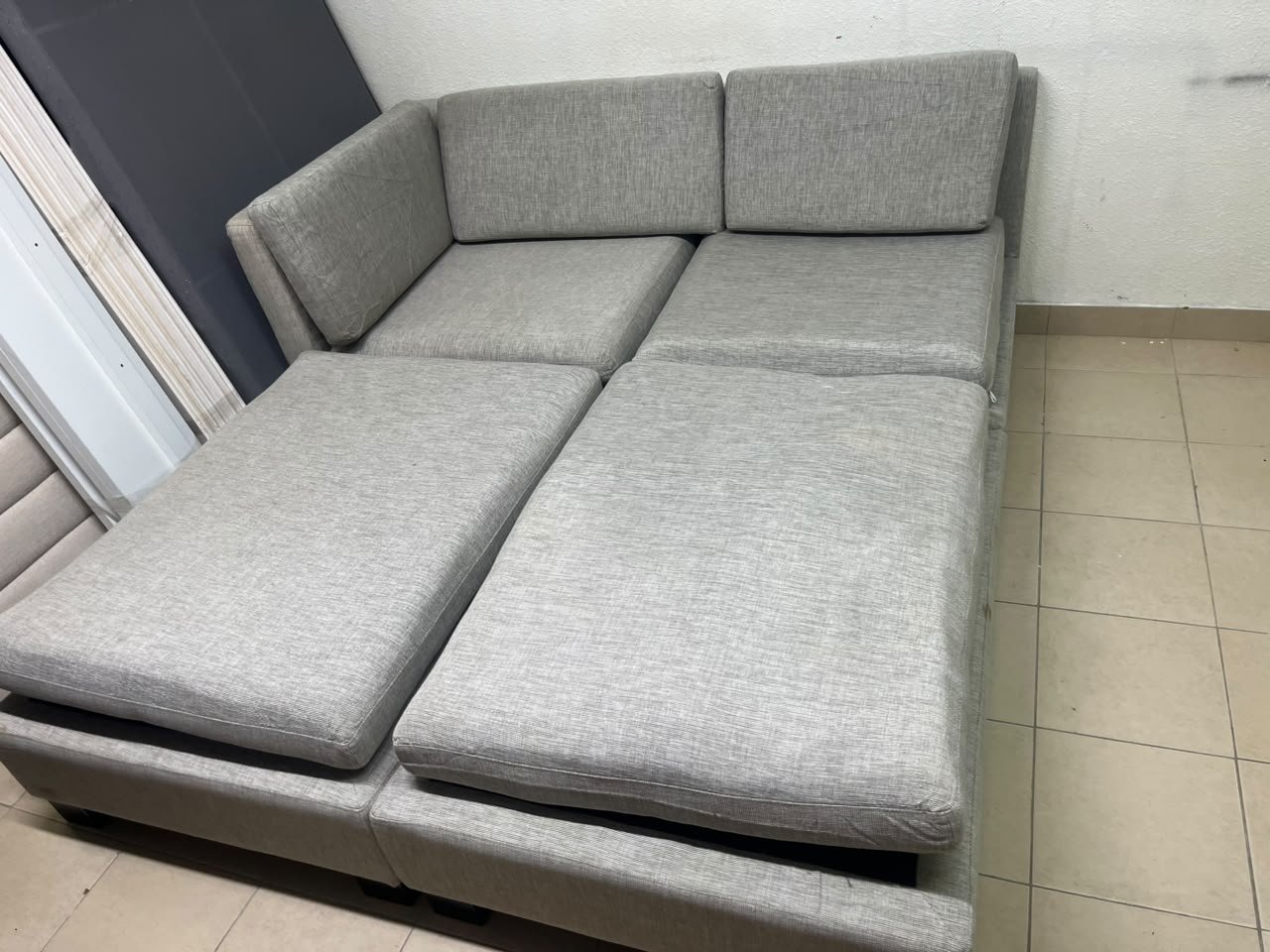 This appears to be a light gray fabric modular sofa, featuring matching ottomans and low, dark block-style legs.