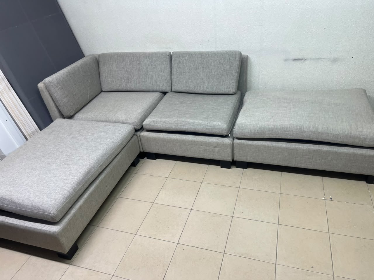 This appears to be a light gray fabric modular sofa, featuring matching ottomans and low, dark block-style legs. - Image 8