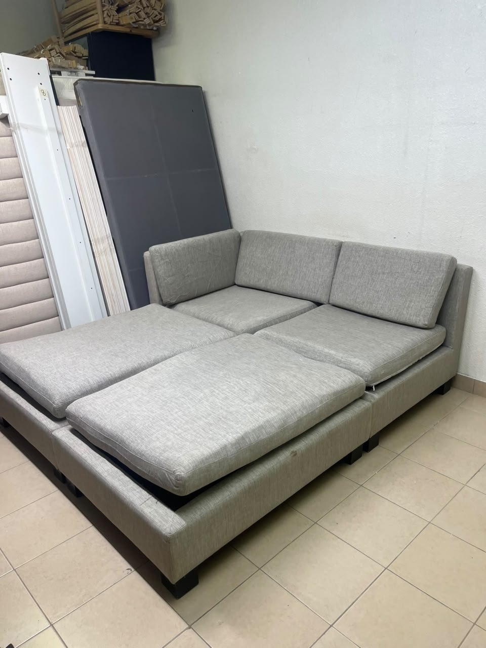 This appears to be a light gray fabric modular sofa, featuring matching ottomans and low, dark block-style legs. - Image 9