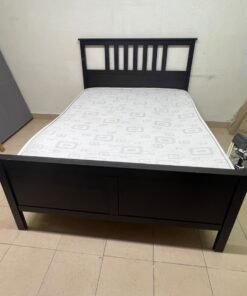 An IKEA "HEMNES" wooden bed frame in a black-brown finish, featuring a slatted headboard and a matching mattress. - Image 2