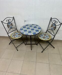 A three-piece black wrought-iron table and chair set, featuring blue and yellow ceramic mosaic tile accents on the round tabletop and the seats of the foldable chairs. - Image 2