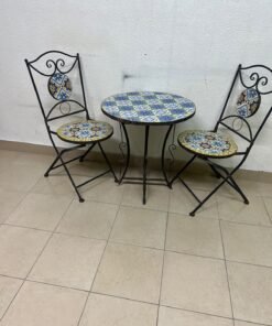 A three-piece black wrought-iron table and chair set, featuring blue and yellow ceramic mosaic tile accents on the round tabletop and the seats of the foldable chairs. - Image 4
