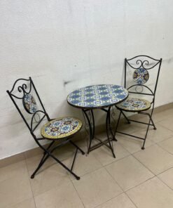 A three-piece black wrought-iron table and chair set, featuring blue and yellow ceramic mosaic tile accents on the round tabletop and the seats of the foldable chairs. - Image 8