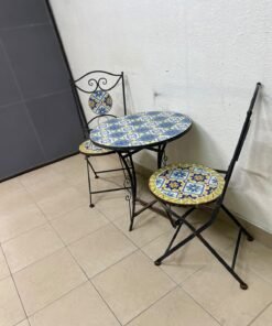 A three-piece black wrought-iron table and chair set, featuring blue and yellow ceramic mosaic tile accents on the round tabletop and the seats of the foldable chairs. - Image 5