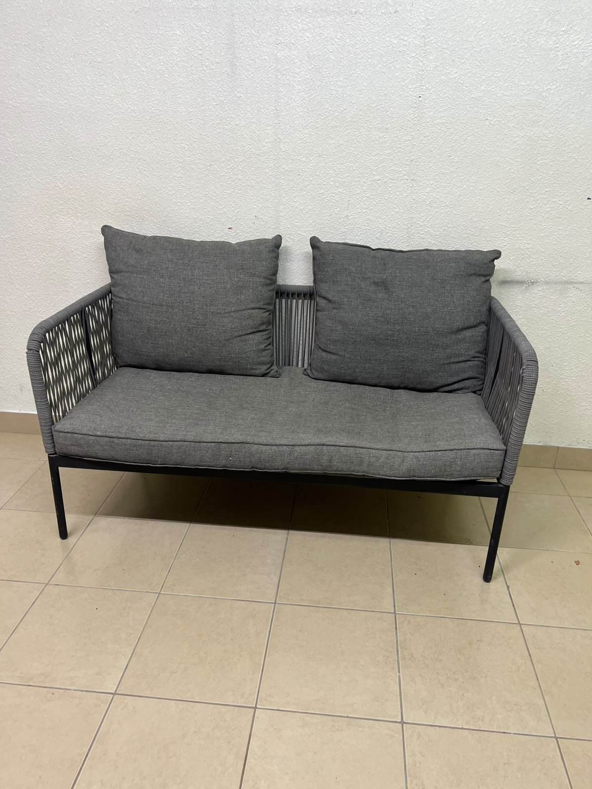 The two-seater outdoor sofa is a modern piece featuring a grey rope-woven design, a black metal frame, and matching back cushions. - Image 2