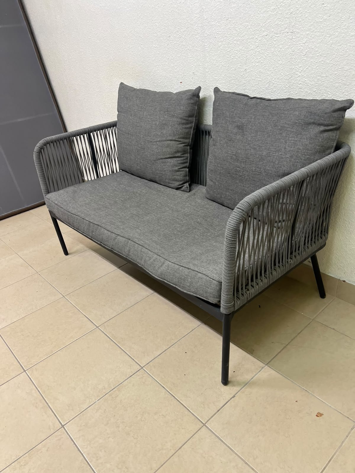 The two-seater outdoor sofa is a modern piece featuring a grey rope-woven design, a black metal frame, and matching back cushions. - Image 4