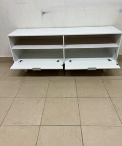 A modern, white, freestanding TV stand featuring angled legs and two large lower storage drawers, topped by open shelves. - Image 5