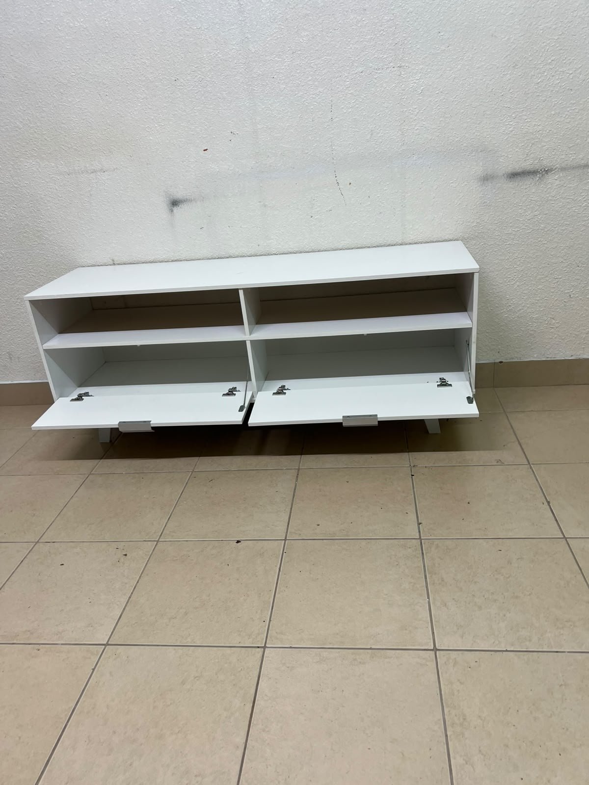 A modern, white, freestanding TV stand featuring angled legs and two large lower storage drawers, topped by open shelves. - Image 6