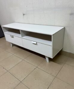 A modern, white, freestanding TV stand featuring angled legs and two large lower storage drawers, topped by open shelves.