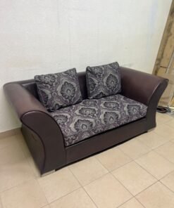 The sofa is designed for two people and upholstered in dark brown faux leather, with a purple and gray damask-patterned fabric covering the seat cushions and matching throw pillows. - Image 3