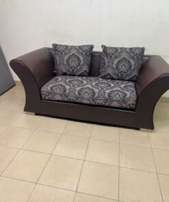 The sofa is designed for two people and upholstered in dark brown faux leather, with a purple and gray damask-patterned fabric covering the seat cushions and matching throw pillows. - Image 5