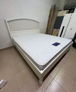 The white IKEA TYSSEDAL bed frame, featuring distinctive vertical wooden slats on the arched headboard and carved legs.