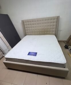 A beige, winged, upholstered bed featuring a button-tufted headboard and nailhead trim. - Image 6