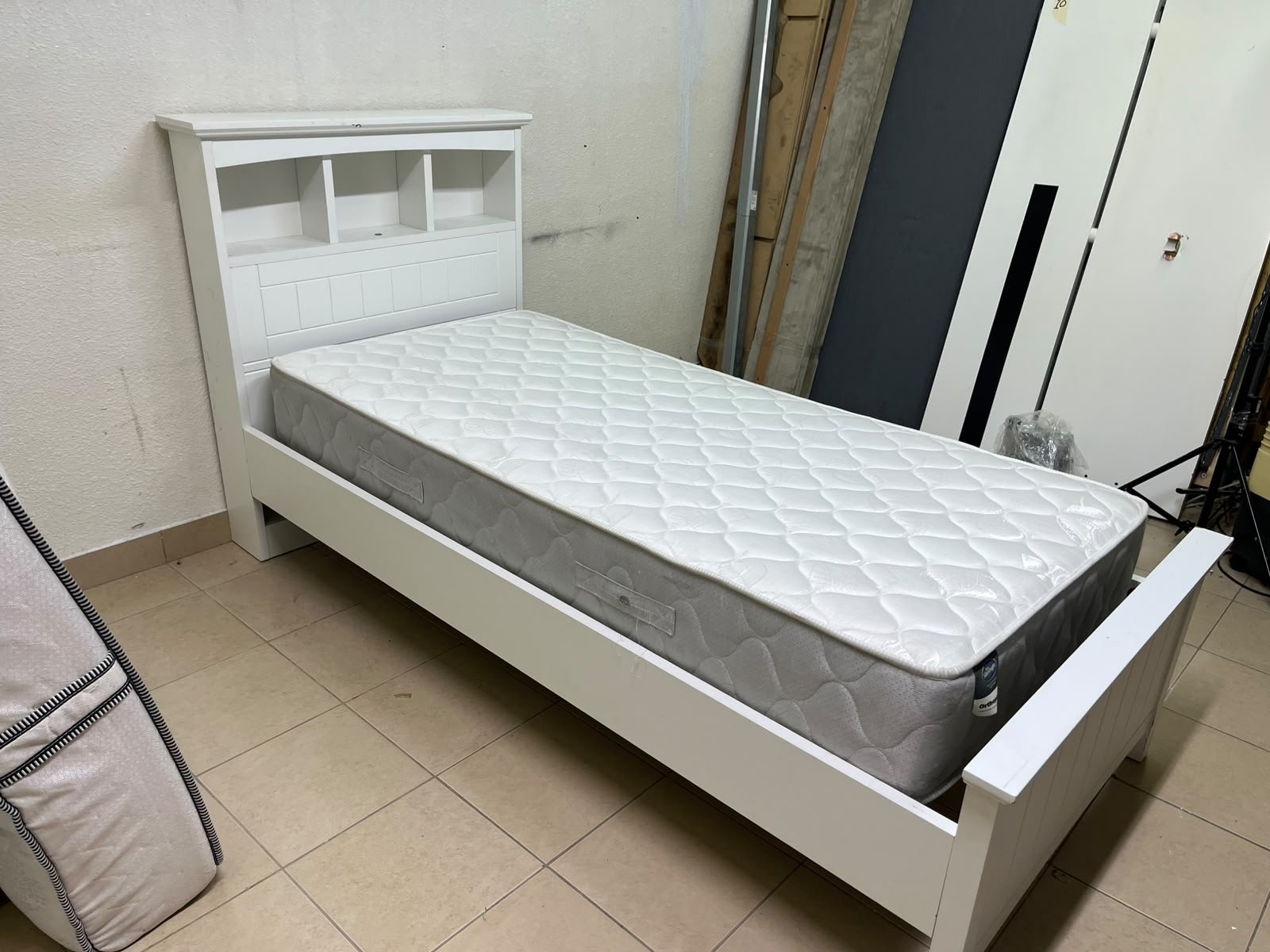 A white wooden single bed frame featuring a headboard with built-in bookshelves, and equipped with a standard padded mattress. - Image 2