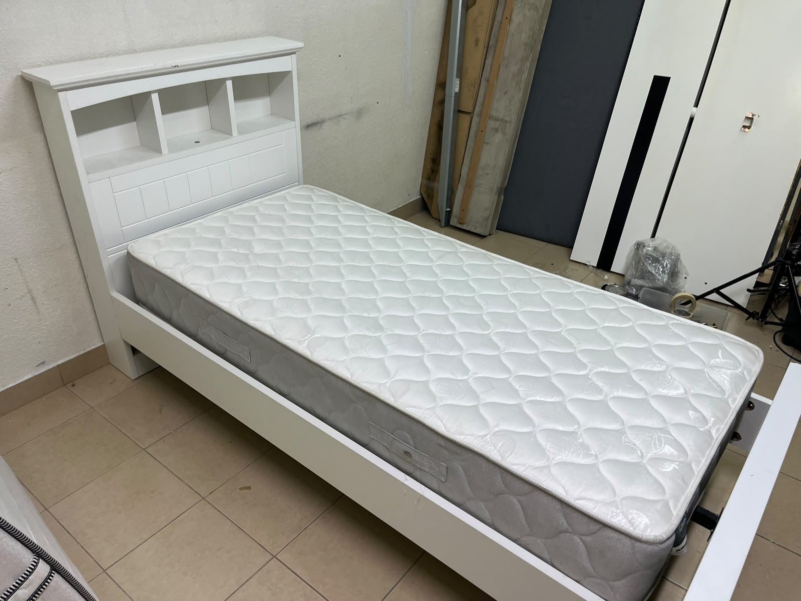 A white wooden single bed frame featuring a headboard with built-in bookshelves, and equipped with a standard padded mattress. - Image 3