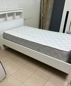 A white wooden single bed frame featuring a headboard with built-in bookshelves, and equipped with a standard padded mattress.