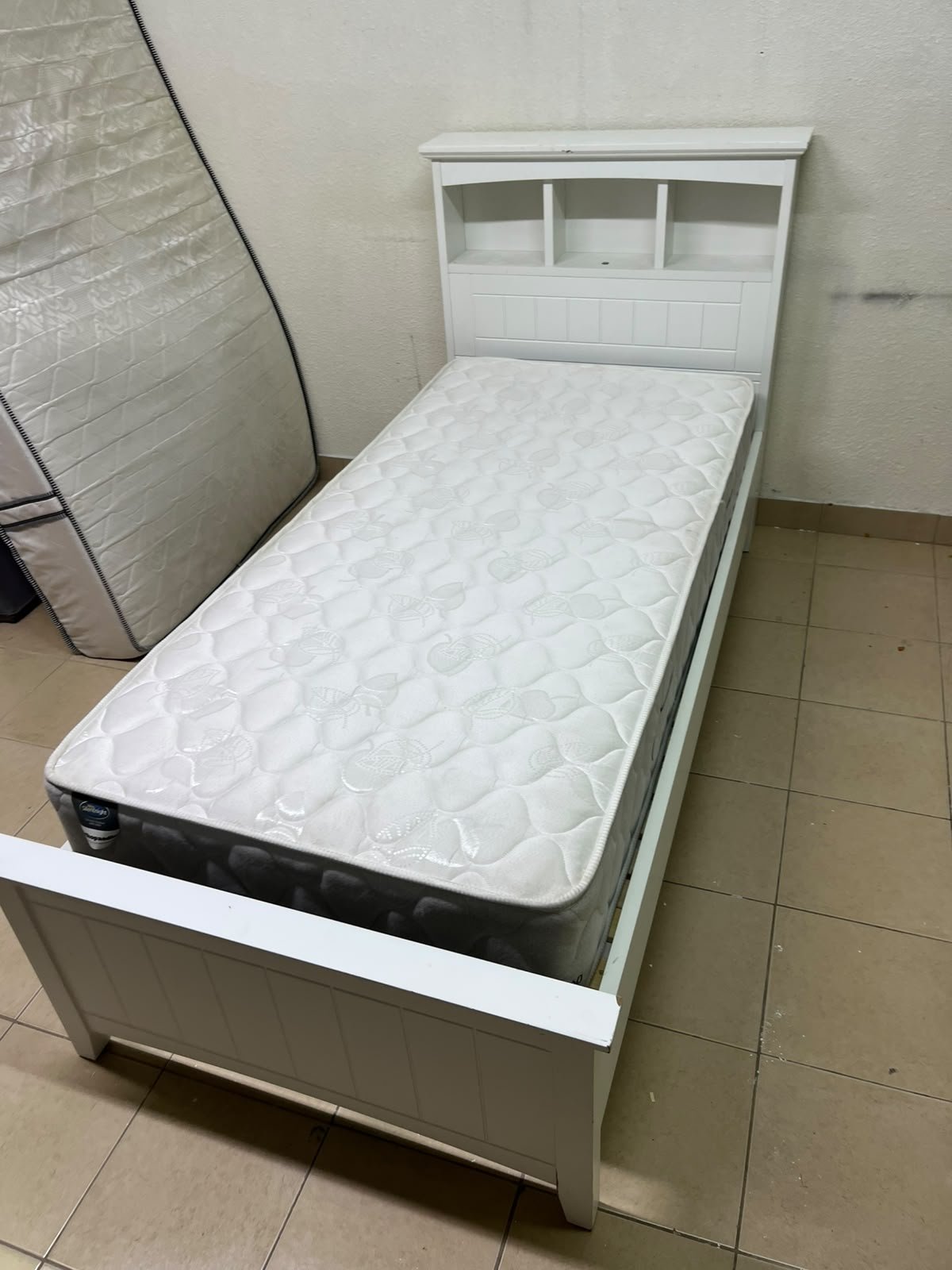 A white wooden single bed frame featuring a headboard with built-in bookshelves, and equipped with a standard padded mattress. - Image 10