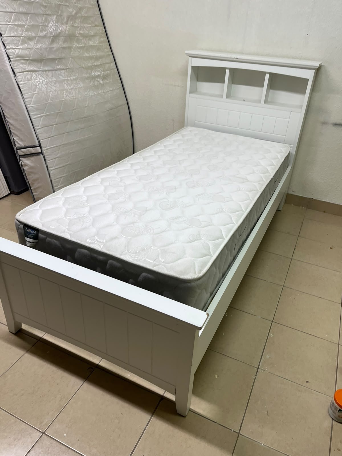 A white wooden single bed frame featuring a headboard with built-in bookshelves, and equipped with a standard padded mattress. - Image 9