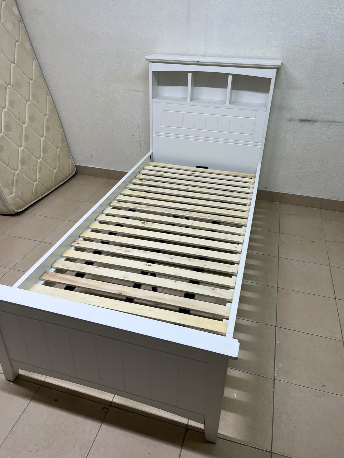 A white wooden single bed frame featuring a headboard with built-in bookshelves, and equipped with a standard padded mattress. - Image 4