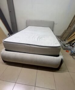 A modern, curved bed frame upholstered in off-white bouclé fabric with dark wood accents, complemented by a patterned, cushioned mattress. - Image 4
