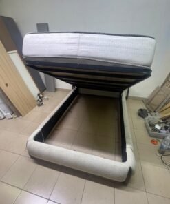 A modern, curved bed frame upholstered in off-white bouclé fabric with dark wood accents, complemented by a patterned, cushioned mattress. - Image 6