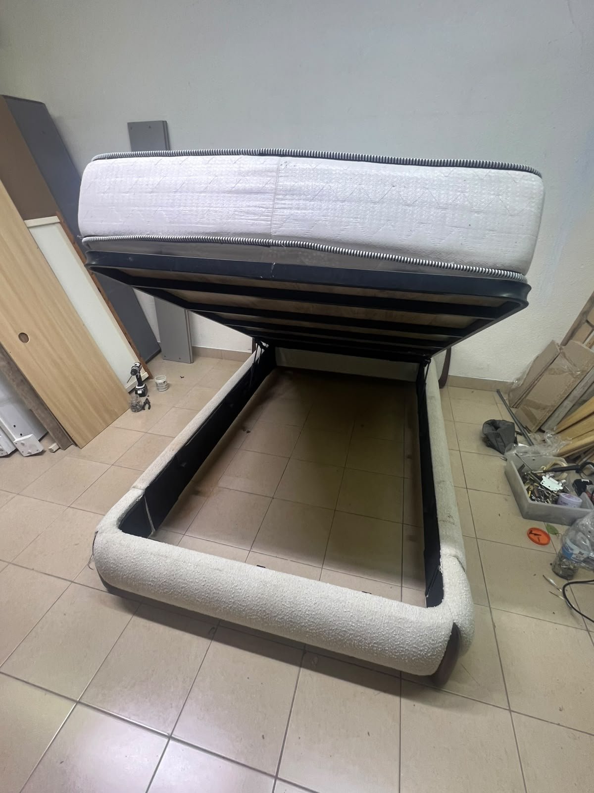 A modern, curved bed frame upholstered in off-white bouclé fabric with dark wood accents, complemented by a patterned, cushioned mattress. - Image 6