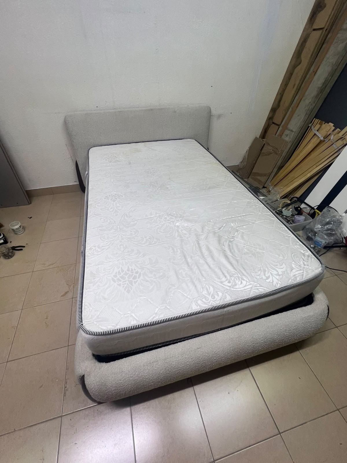 A modern, curved bed frame upholstered in off-white bouclé fabric with dark wood accents, complemented by a patterned, cushioned mattress. - Image 7