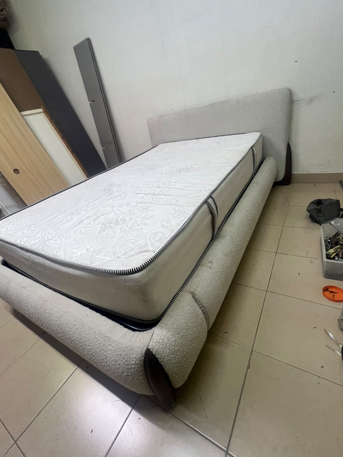 A modern, curved bed frame upholstered in off-white bouclé fabric with dark wood accents, complemented by a patterned, cushioned mattress. - Image 9