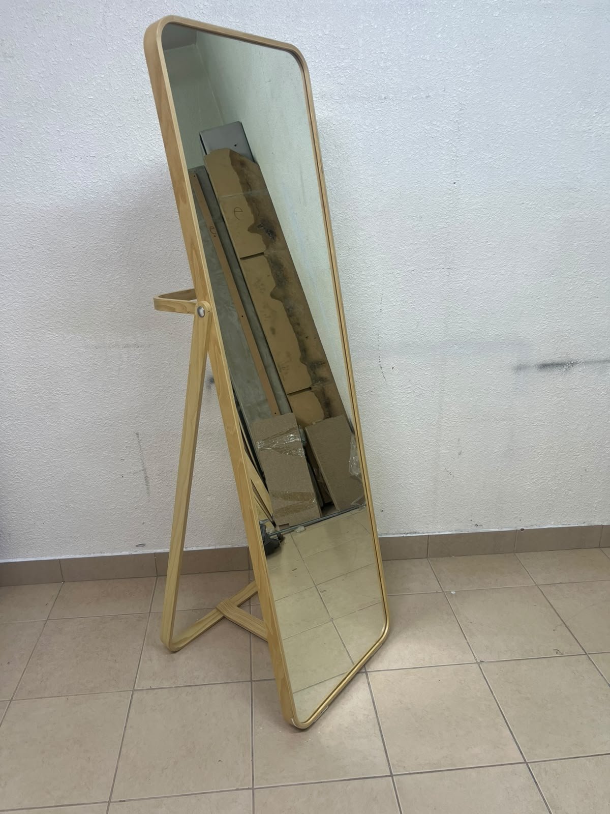 The IKEA IKORNNES ash wood standing mirror, featuring a distinctive rounded wooden frame and a hanging rail integrated into the rear stand.