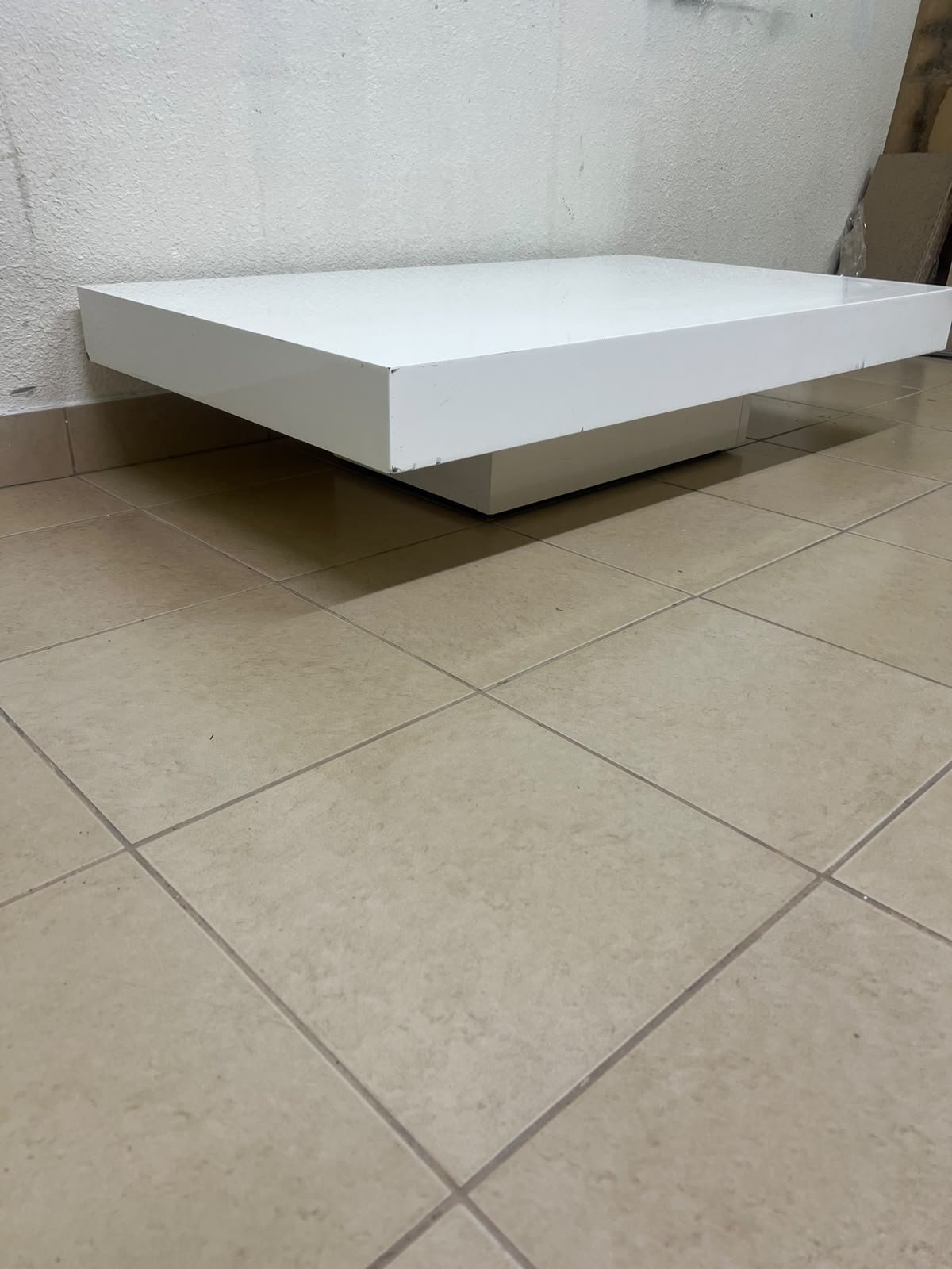 A modern, low, rectangular white coffee table featuring a minimalist design, a recessed base, and a smooth lacquered finish.