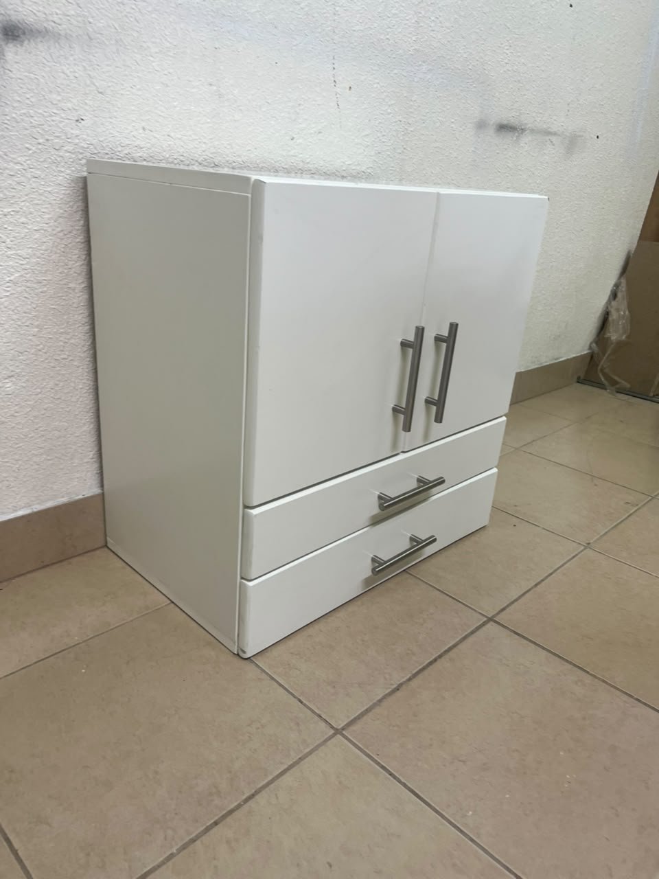 A white wooden storage cabinet featuring two upper doors and two lower drawers equipped with rectangular silver handles. - Image 2