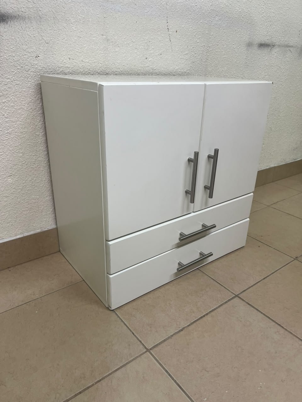 A white wooden storage cabinet featuring two upper doors and two lower drawers equipped with rectangular silver handles. - Image 4