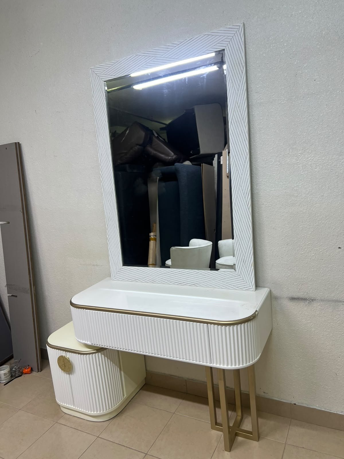 A modern vanity (makeup station) featuring a white striped design, a gold frame, and illuminated accents—a piece of contemporary bedroom décor.
