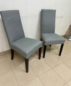 A modern "Parsons" style dining chair, featuring a high back, gray upholstery, and dark wood legs.