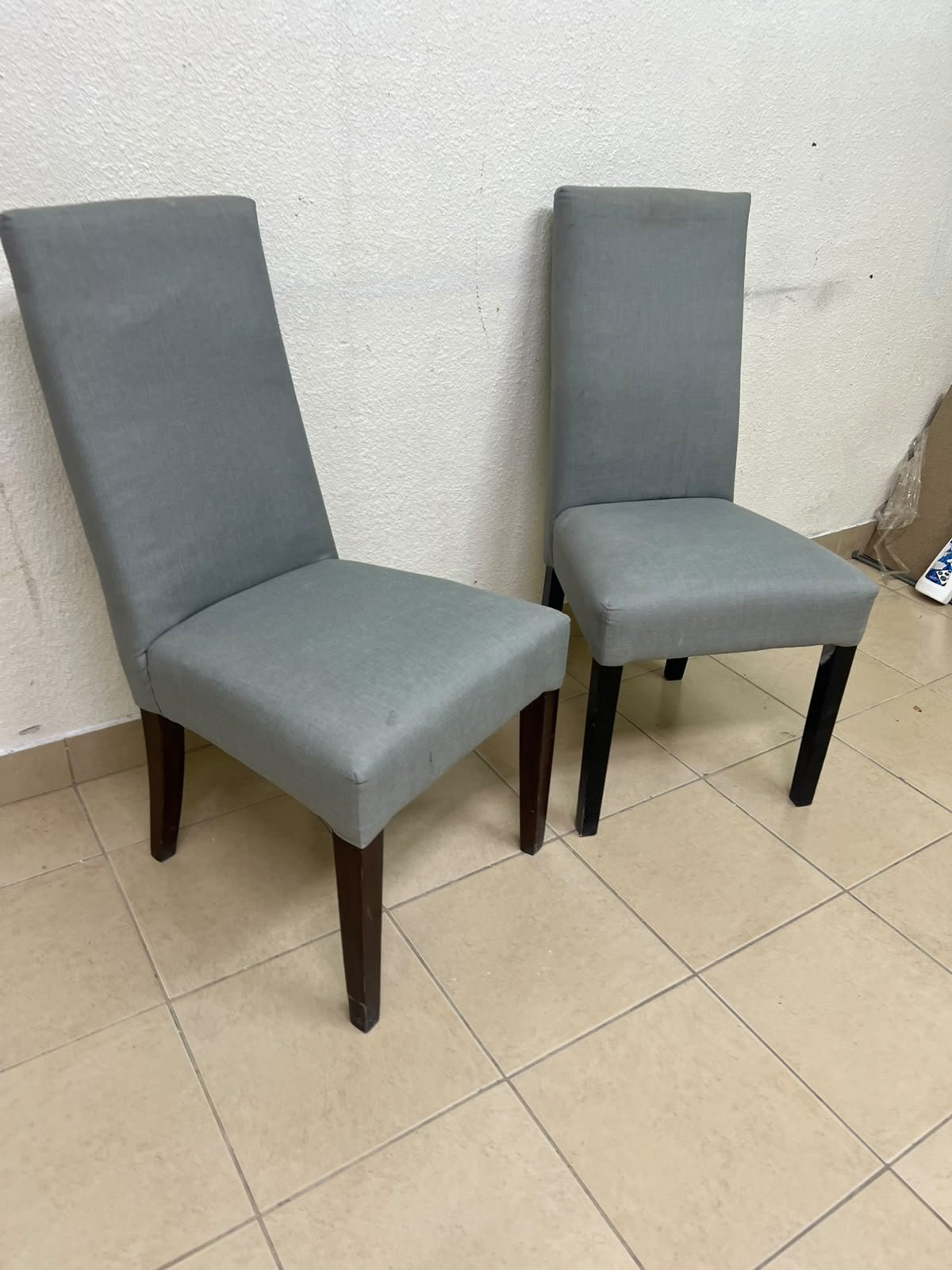 A modern "Parsons" style dining chair, featuring a high back, gray upholstery, and dark wood legs.