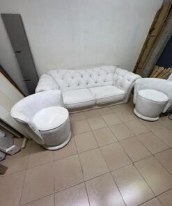 A modern living room furniture set in an off-white or cream hue, featuring a cushioned sofa with a curved back, complemented by matching barrel-style swivel chairs with round bases. - Image 4
