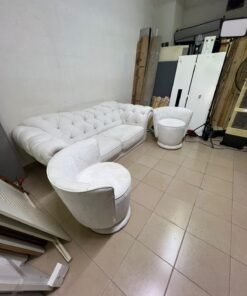A modern living room furniture set in an off-white or cream hue, featuring a cushioned sofa with a curved back, complemented by matching barrel-style swivel chairs with round bases. - Image 5