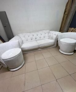 A modern living room furniture set in an off-white or cream hue, featuring a cushioned sofa with a curved back, complemented by matching barrel-style swivel chairs with round bases. - Image 8