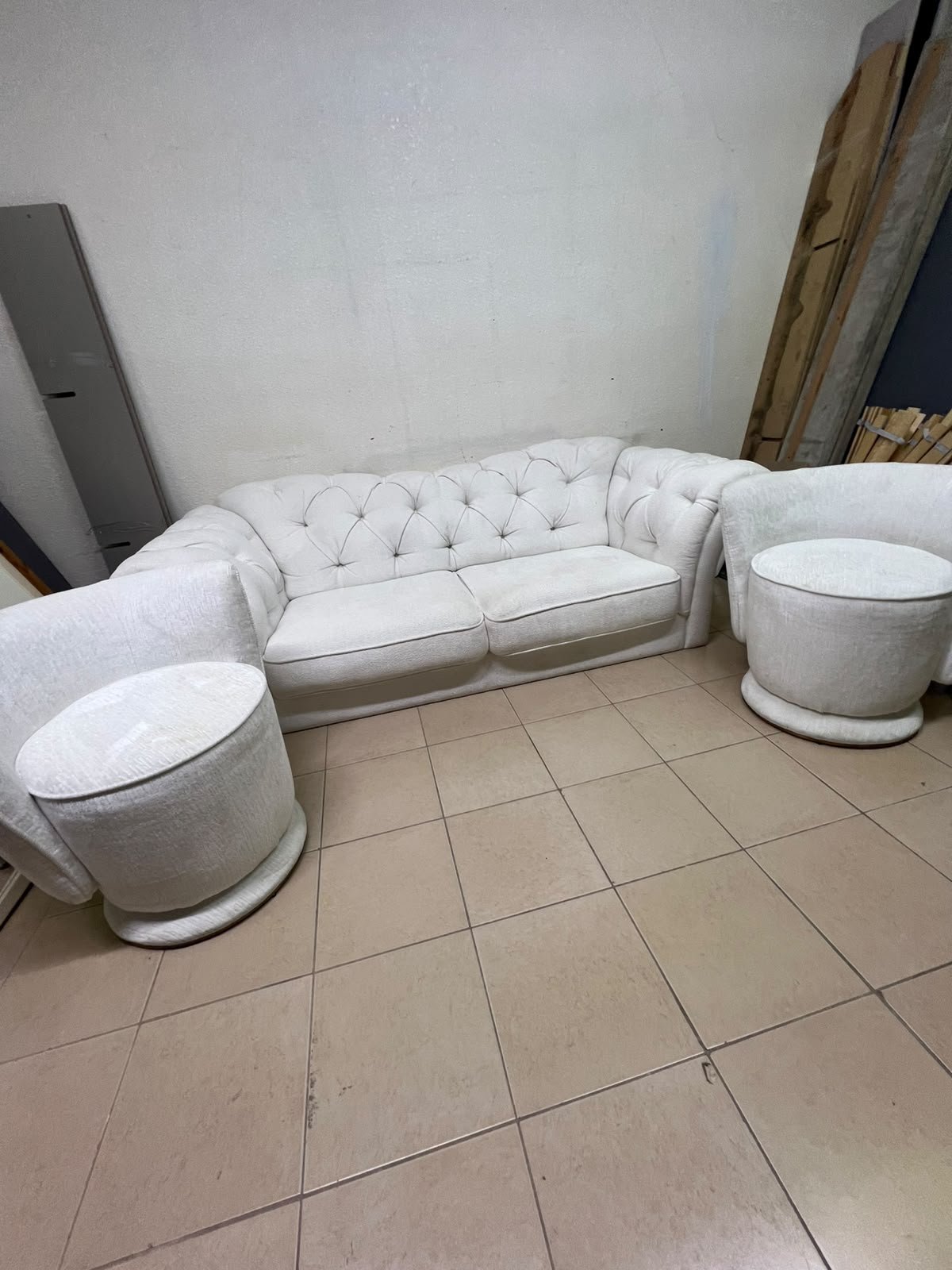 A modern living room furniture set in an off-white or cream hue, featuring a cushioned sofa with a curved back, complemented by matching barrel-style swivel chairs with round bases. - Image 8