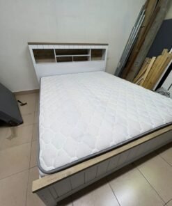 A white wooden King-size bed frame featuring an integrated headboard with shelves, accompanied by a matching padded mattress.